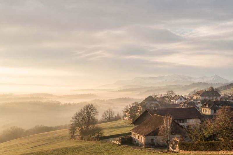 A Swiss village set in rolling countryside, under the haze of a golden morning